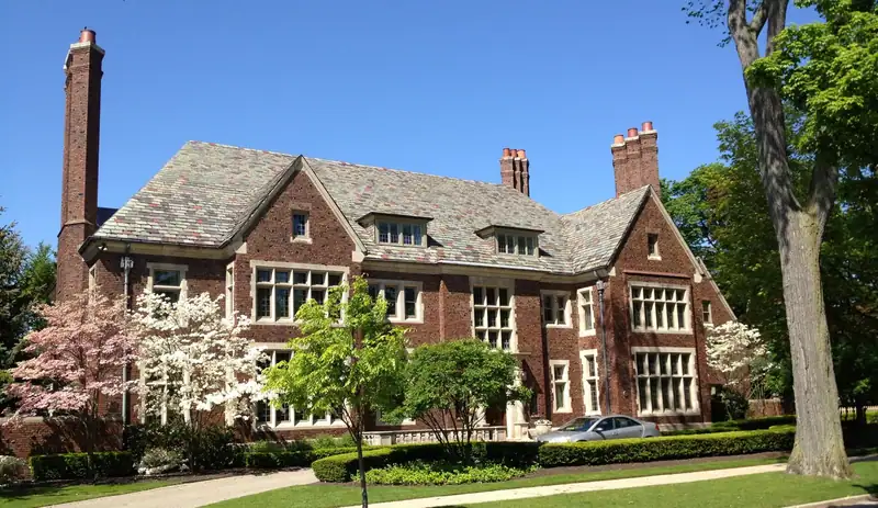 A brick Jacobean-style house behind a lawn