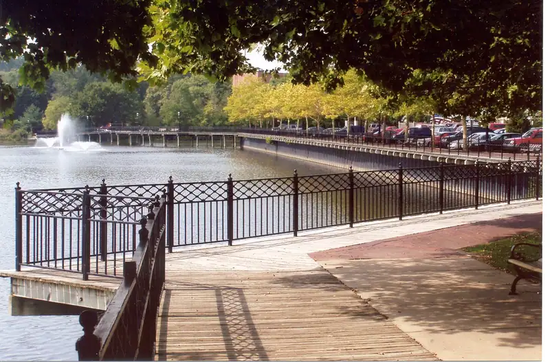 A riverwalk railing beside the Kalamazoo River with a fountain