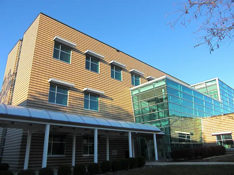 A modern campus building with glass walls under a blue sky