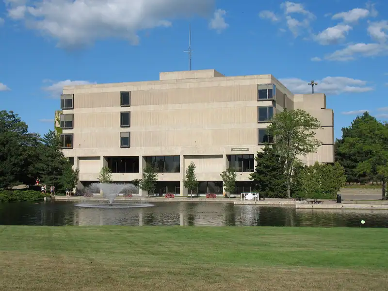 A campus building beside a pond on a sunny day