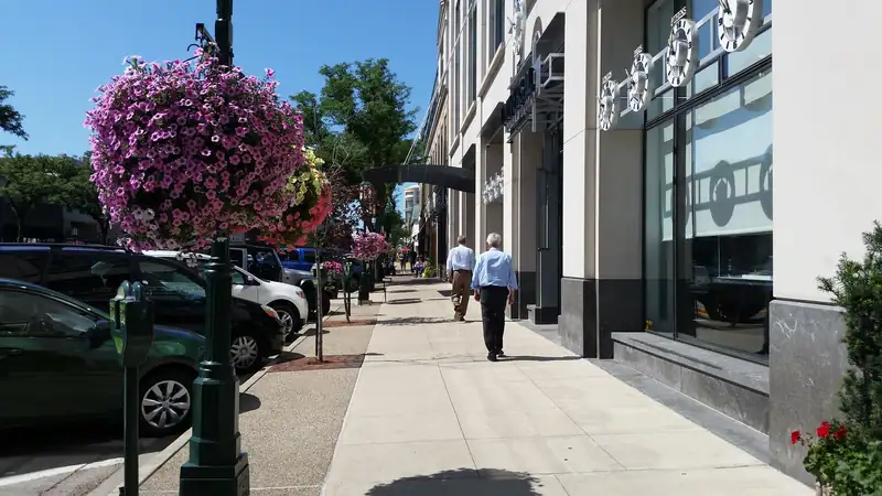 A sidewalk with hanging flower baskets and storefronts