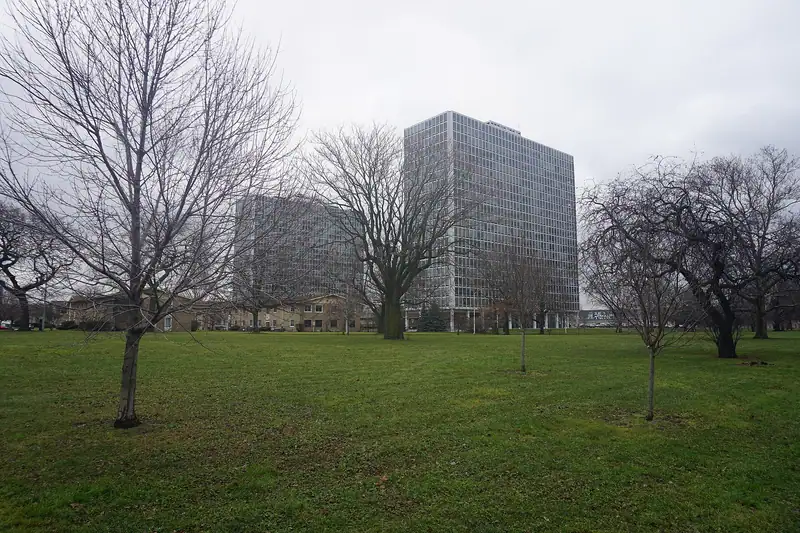 An open park lawn with trees and towers beyond