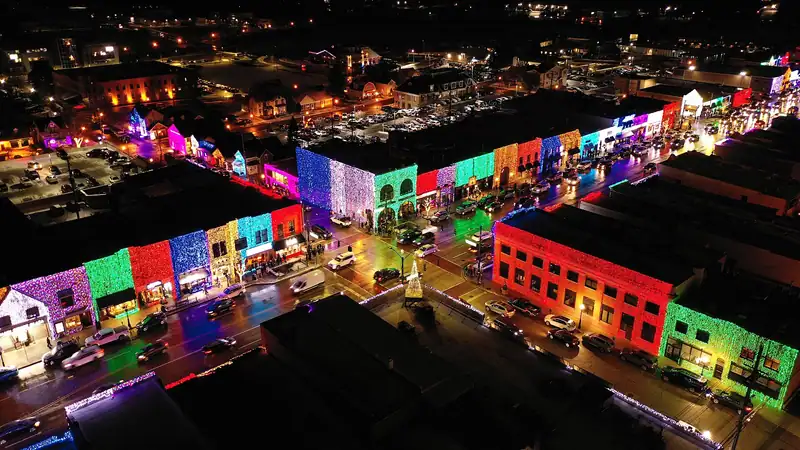 Downtown buildings outlined in colorful holiday lights at night