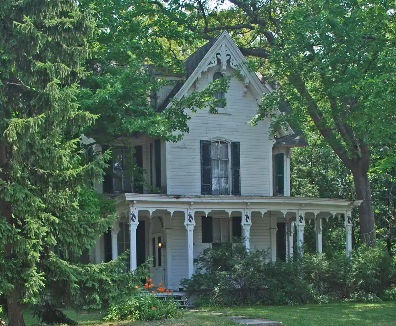 A white Victorian house among green trees