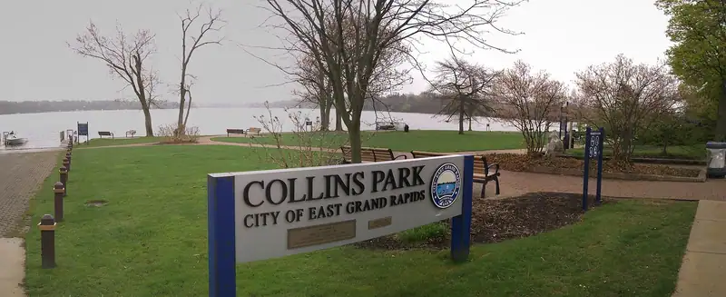 A lakeside park sign with Reeds Lake behind it