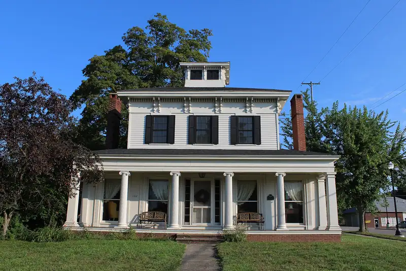 A white Greek Revival house with a porch