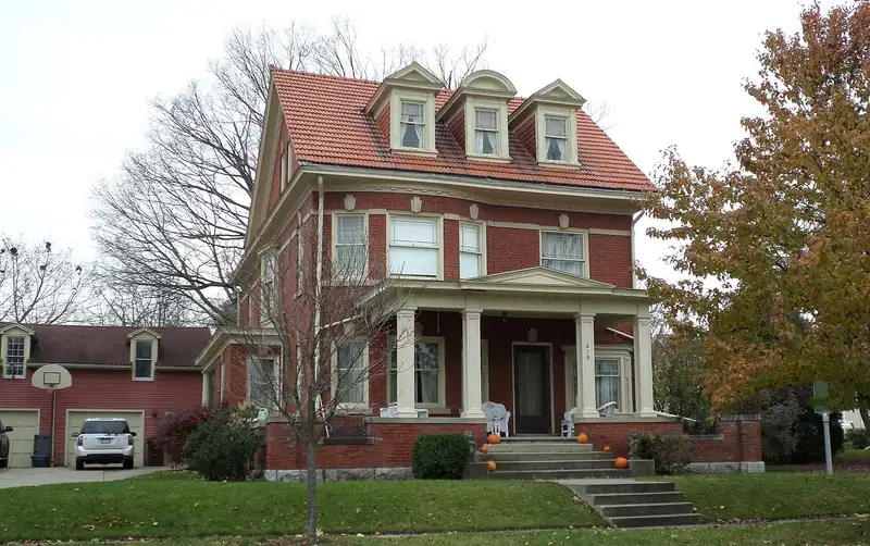 A large brick house with a front porch and trees
