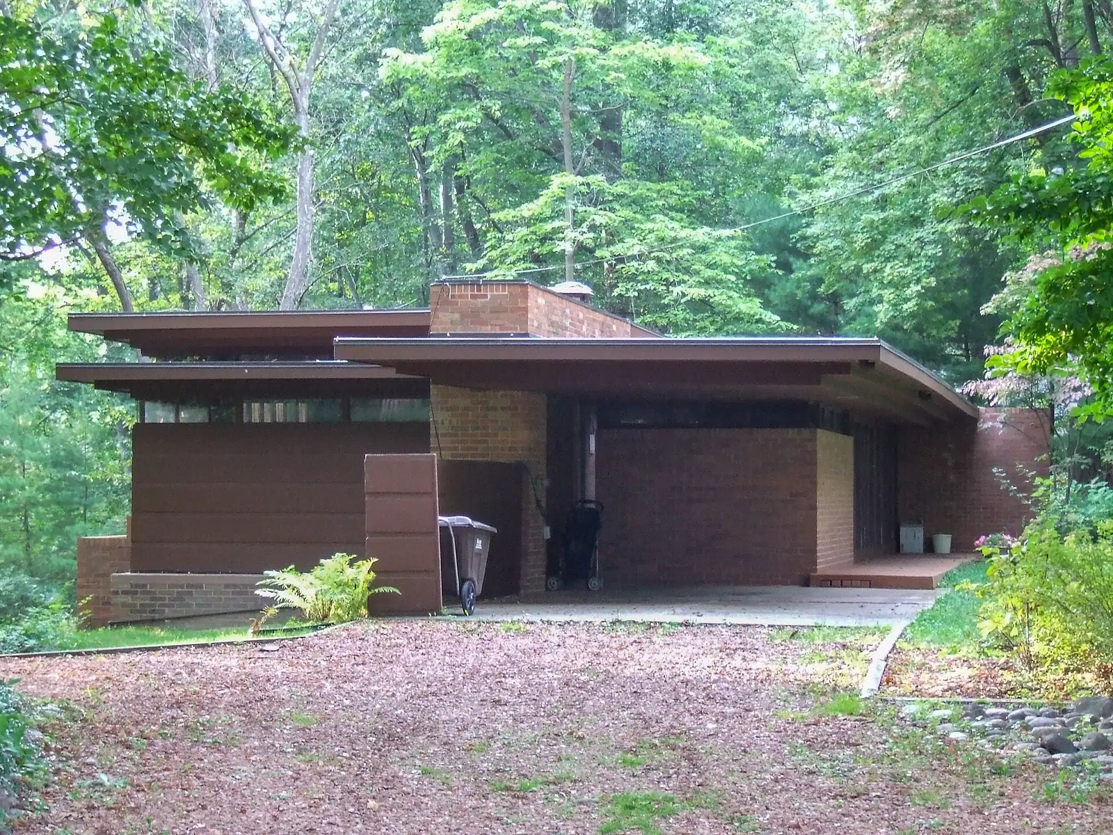 A low modern house with a long overhanging roof among trees