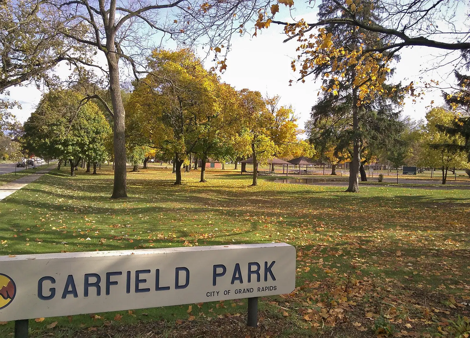 A park sign and lawn with fall trees