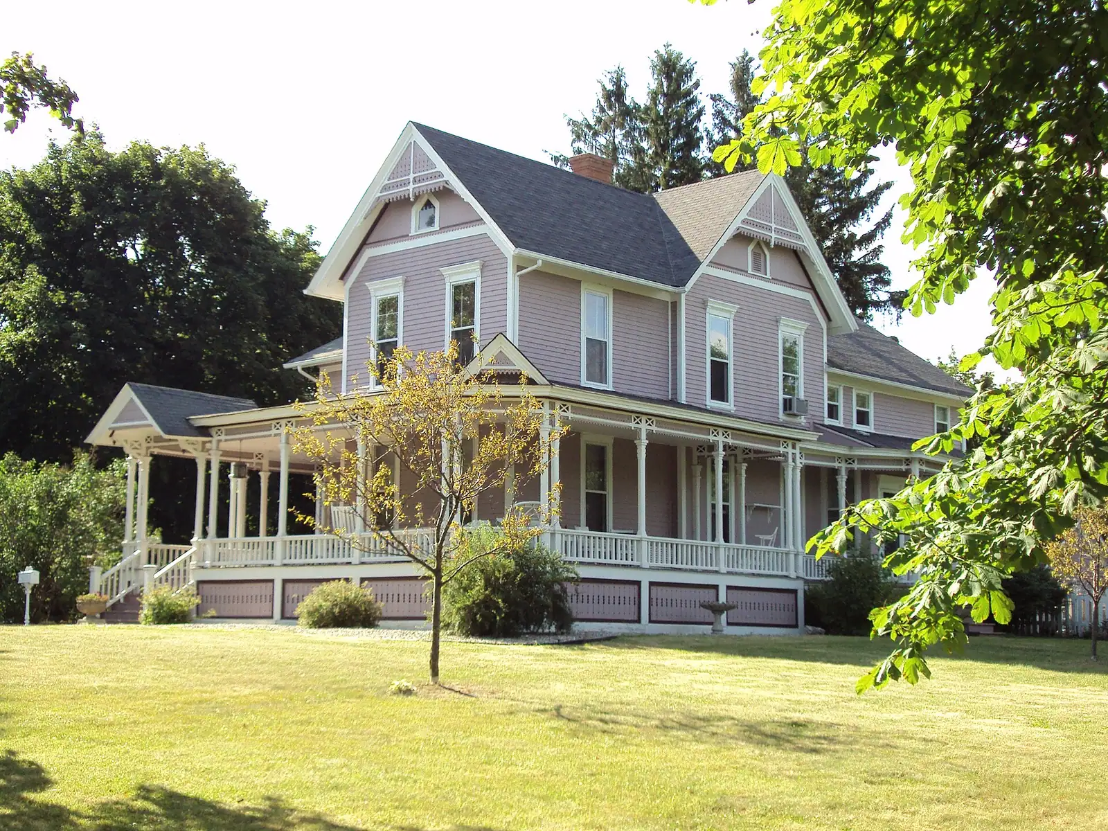 A gray Victorian house with a wraparound porch