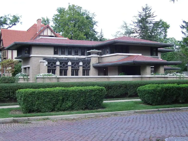 A low brick Prairie-style house behind trimmed hedges