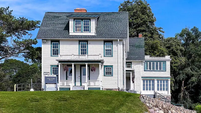 A white historic farmhouse with a porch