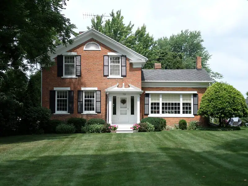 A red brick house with white trim and a lawn