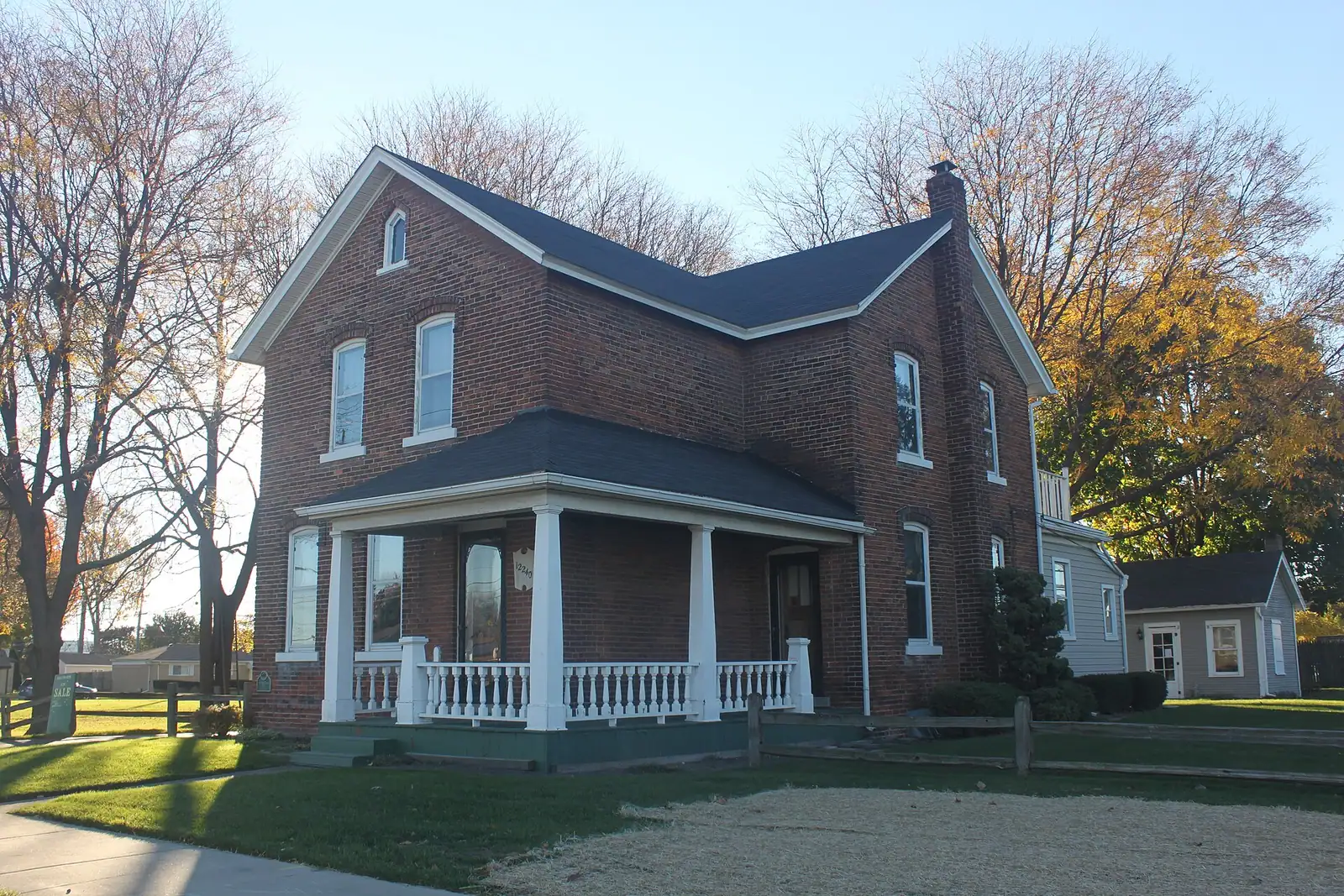 A red brick historic farmhouse with a porch