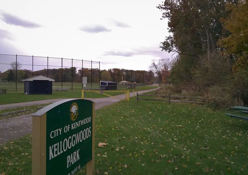 A city park sign and lawn edged by woods