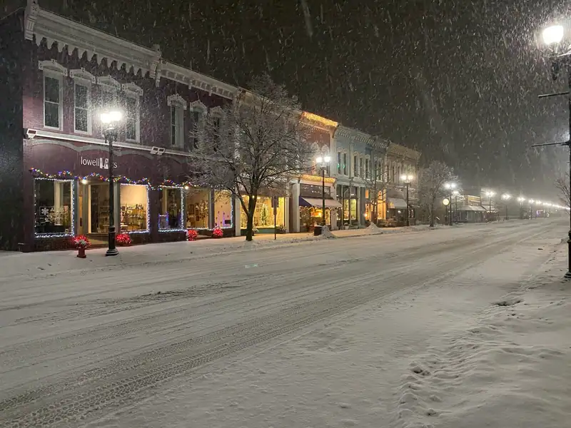 A lit-up downtown street in falling snow