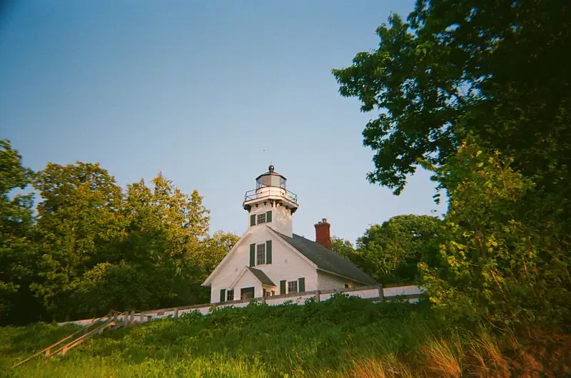 A white wood-frame lighthouse among trees