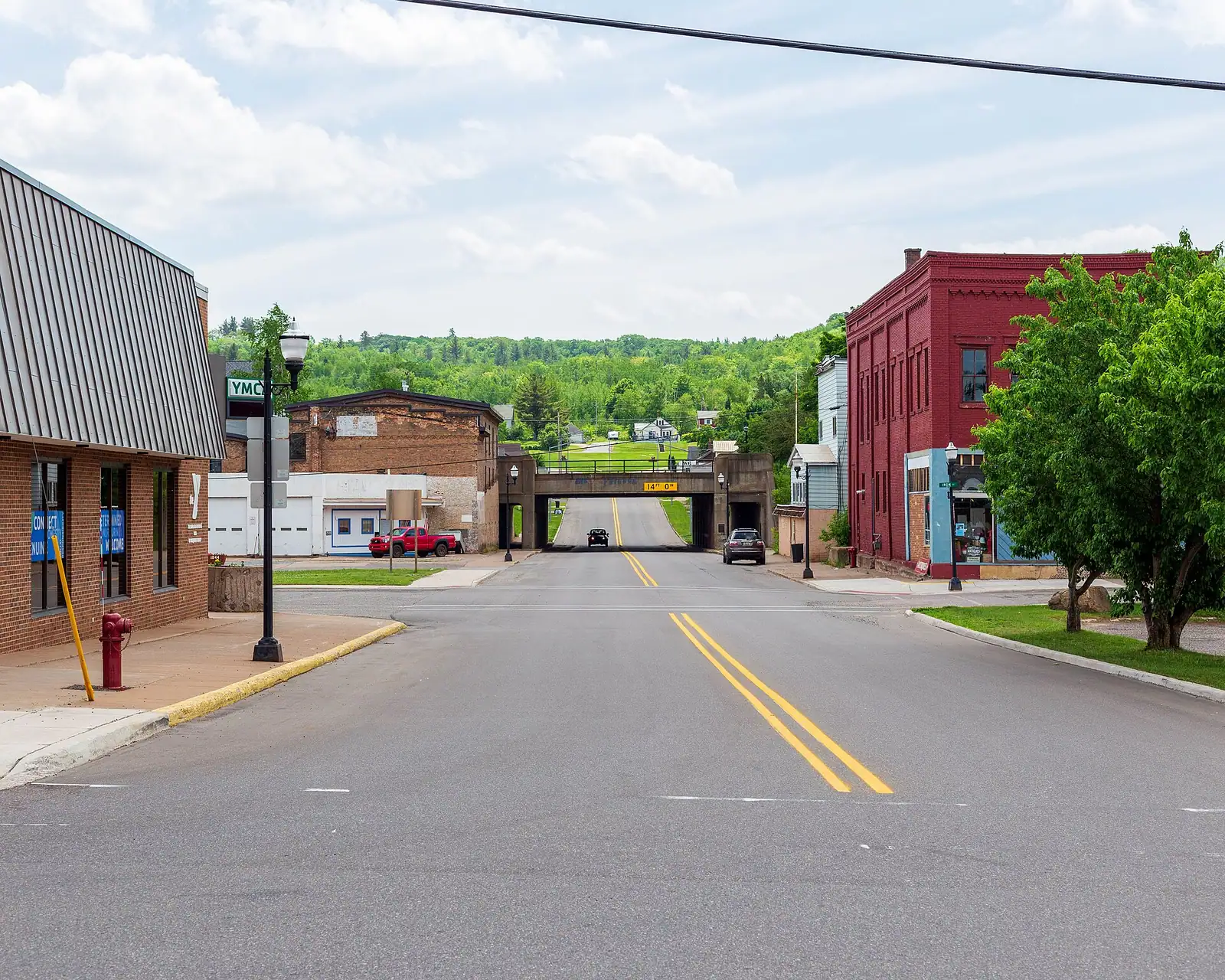 A small downtown street with brick storefronts and green hills