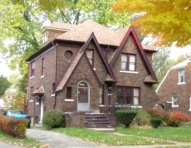 A brick Tudor-style house with a front lawn
