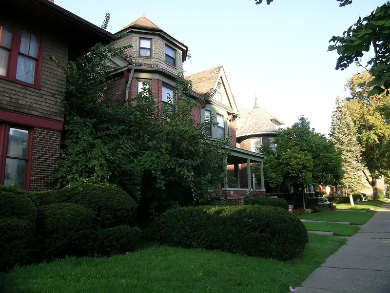 Historic brick homes behind trees and hedges